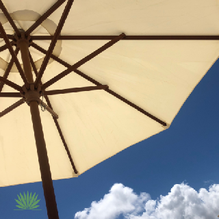 beige patio umbrella against blue sky with clouds